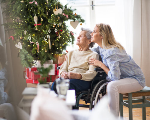 A senior woman in wheelchair with a health visitor at home at Christmas time.